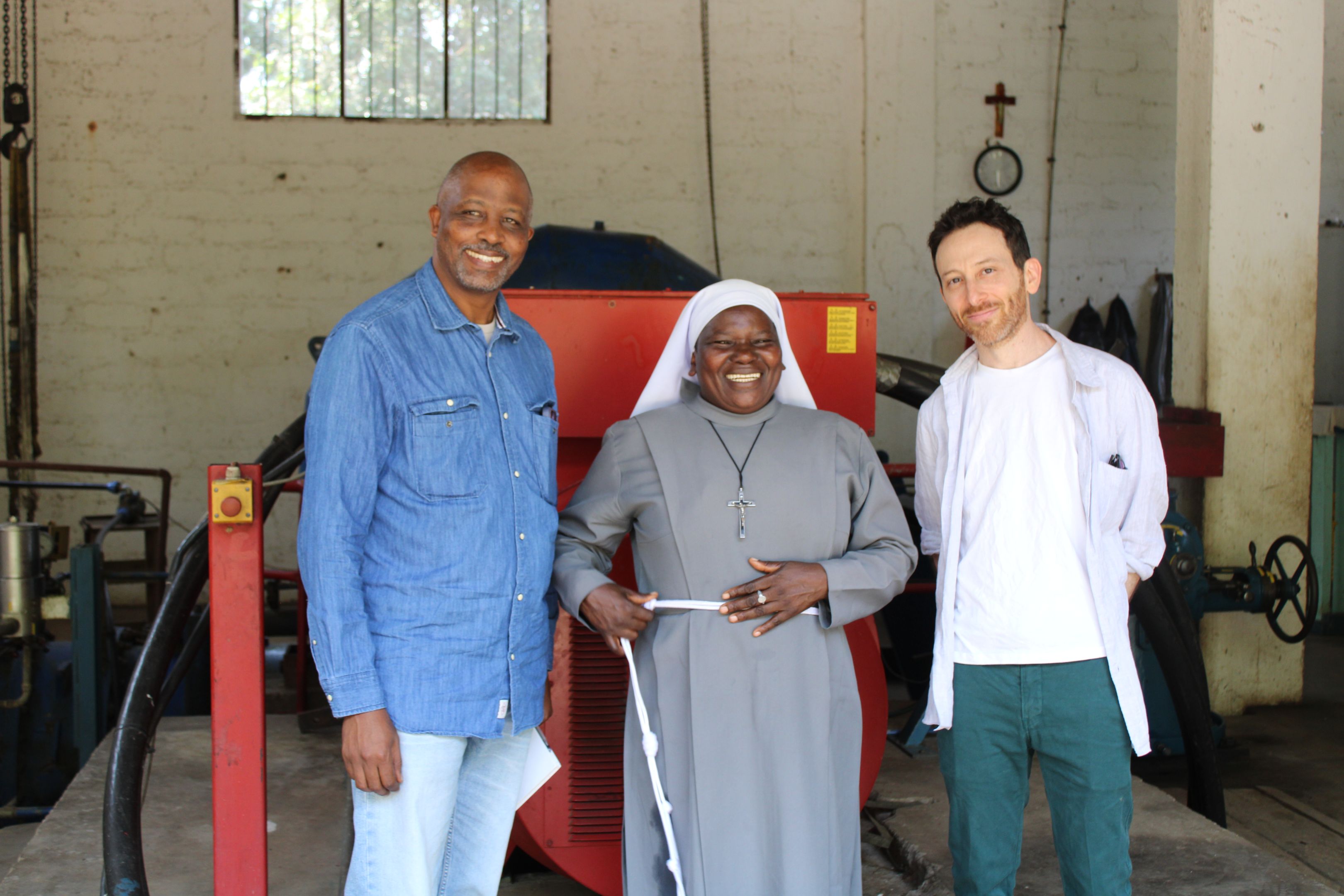 Two smiling men and a smiling woman in a nun's habit. 