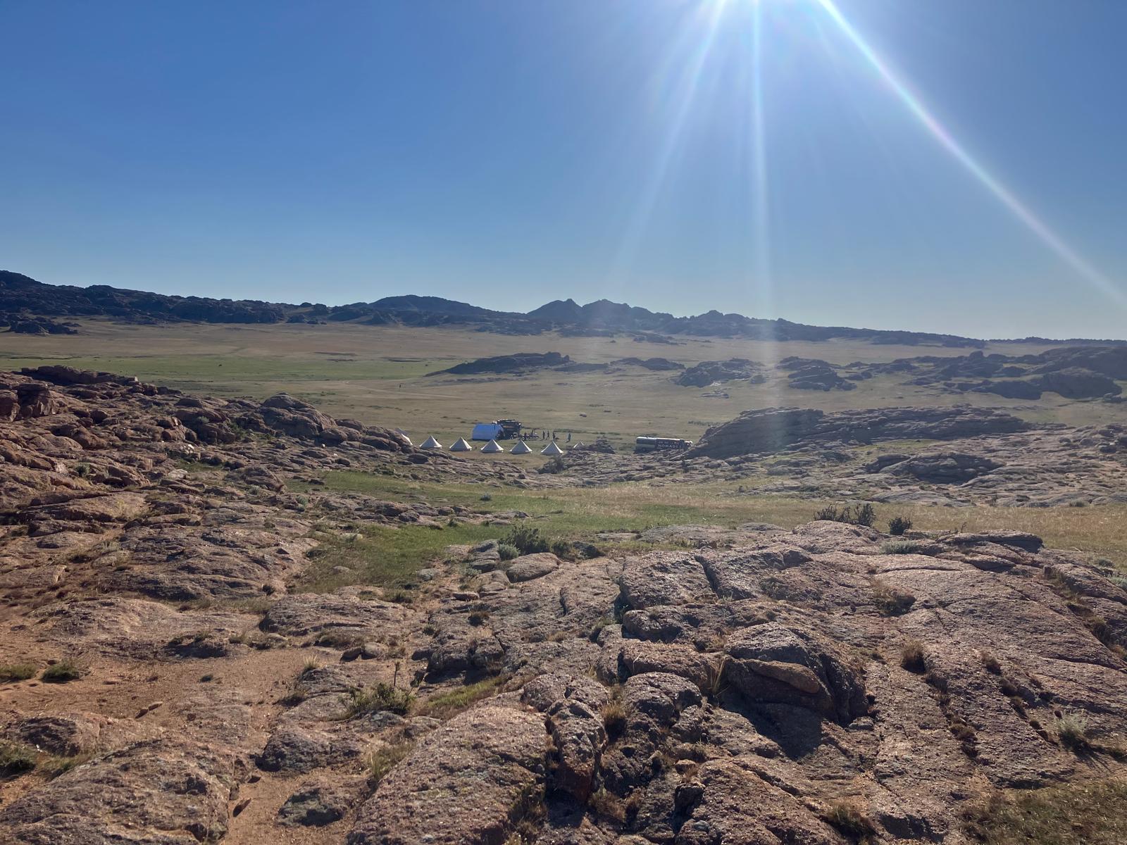 Sun rays across a rocky and grassy landscape in Mongolia