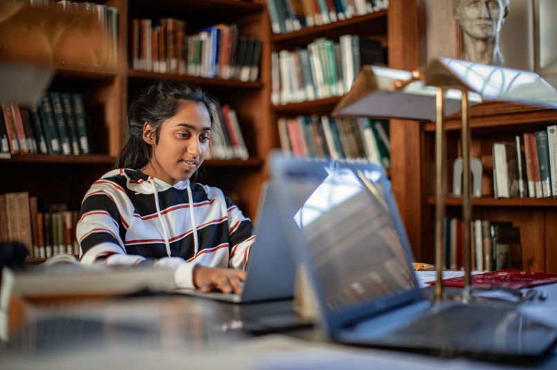 a student in the library working on a laptop