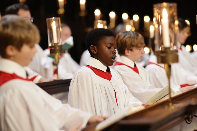 a group of choristers in white and red robes singing