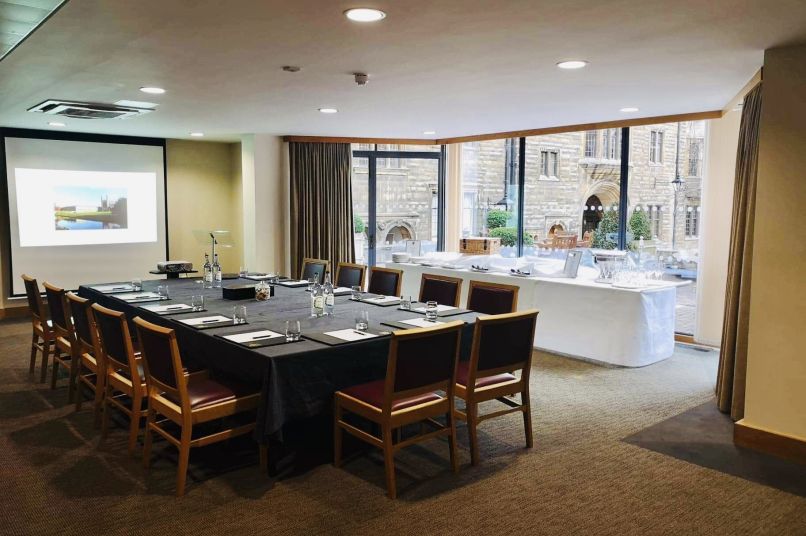 a meeting room with a table and chairs and large windows to the right