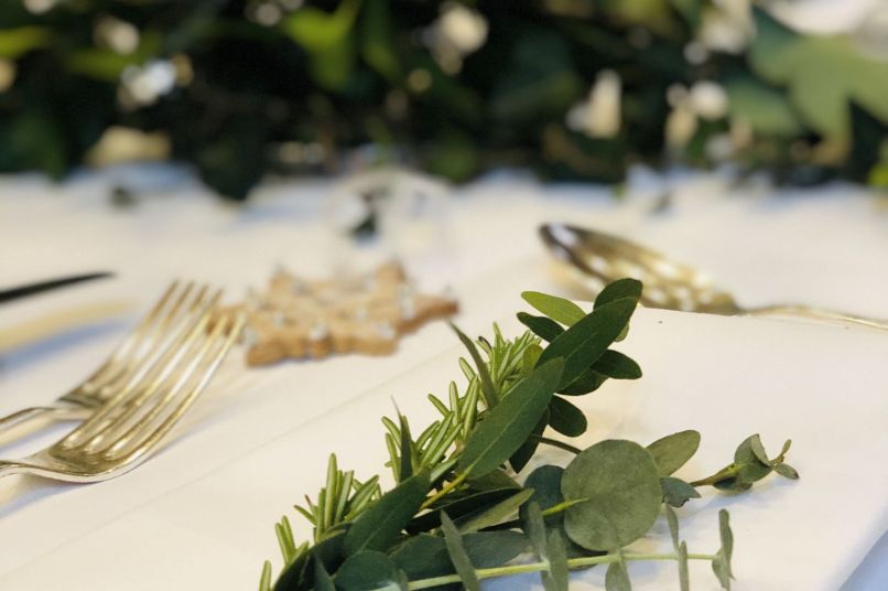 Eucalyptus and rosemary decorate a formal table with cutlery