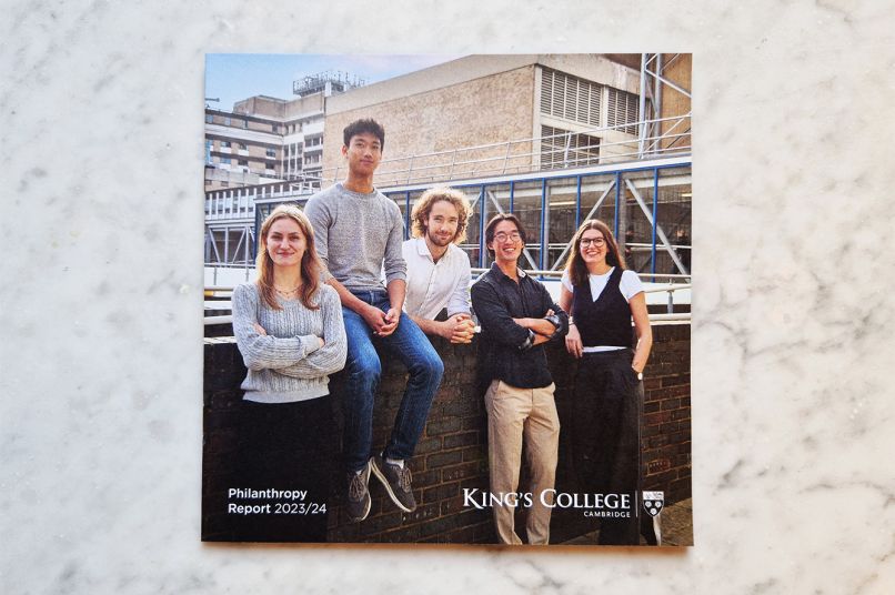 A copy of the Philanthropy Report which is a square magazine with five smiling students on the cover. The magazine is on a marble surface.