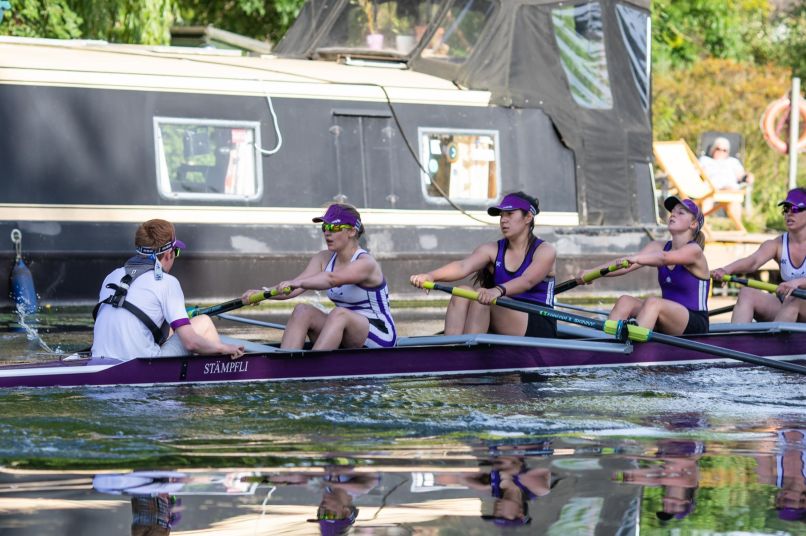 Students rowing on the Cam with a canal boat in the background. 