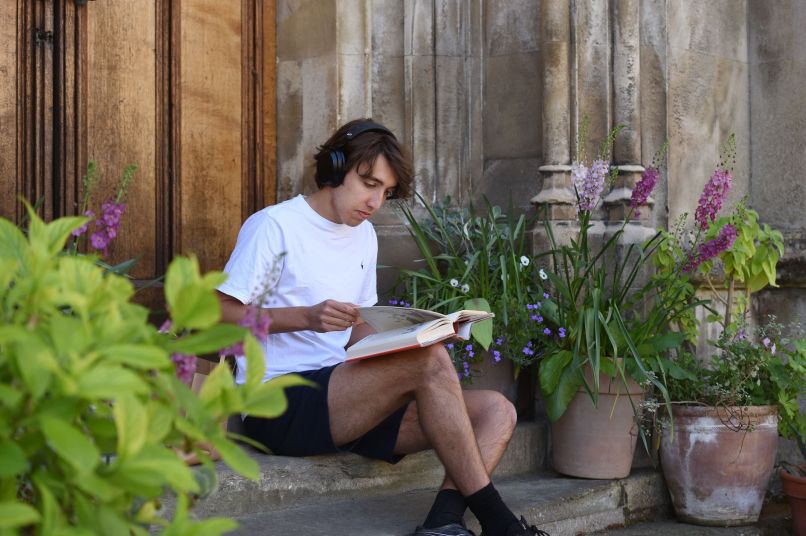 a male student wearing headphones and reading a book