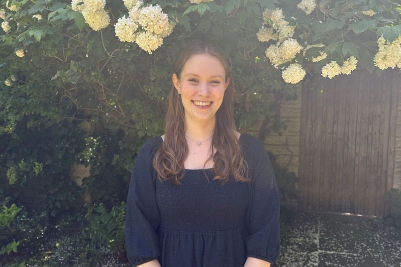 Bethan standing in front of flowers