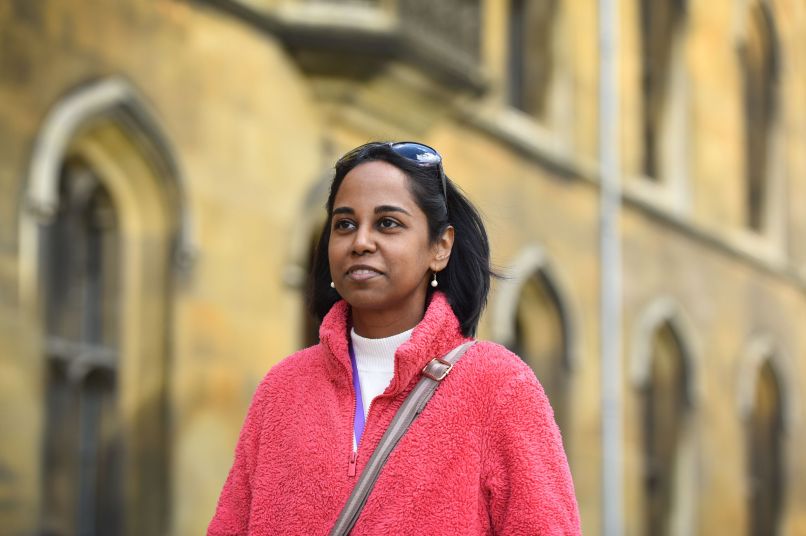 A female graduate student wearing a casual pink jumper