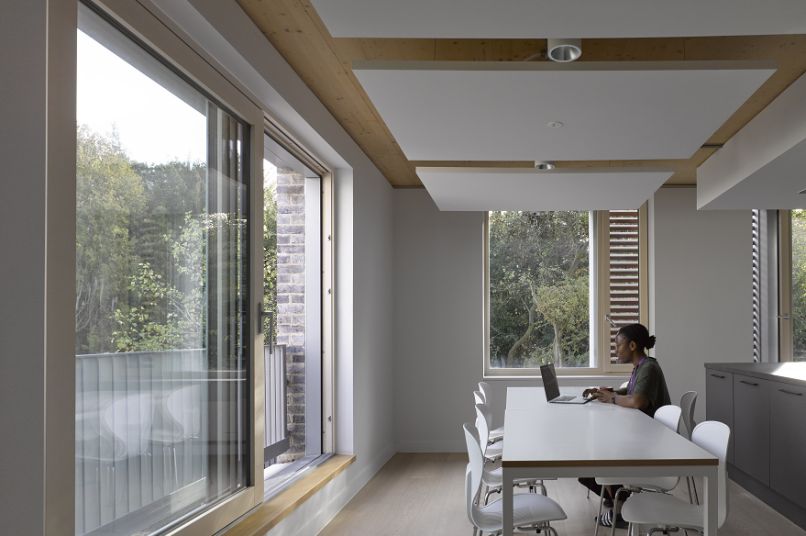 A graduate student sitting in a large modern room looking out of the window