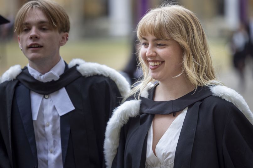 Two smiling students wearing academic robes
