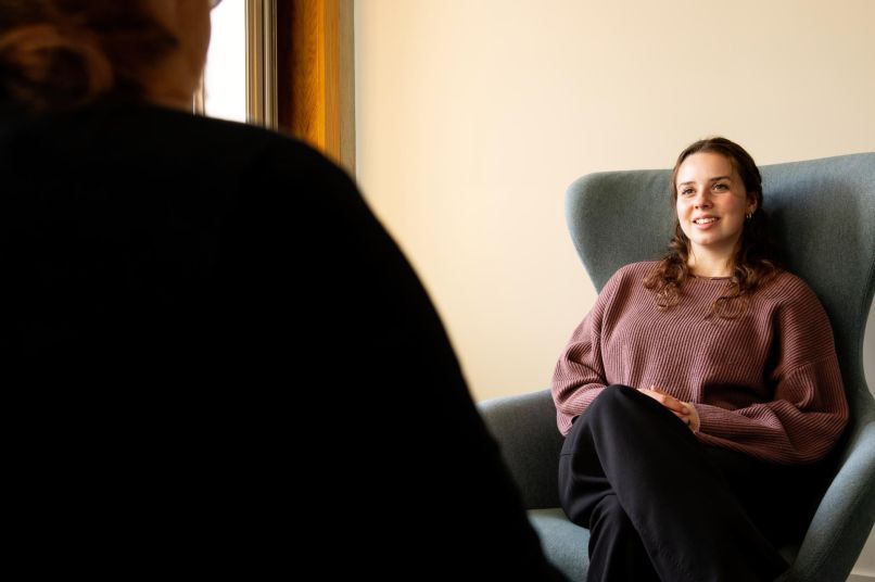 A woman in a chair listening attentively to another person
