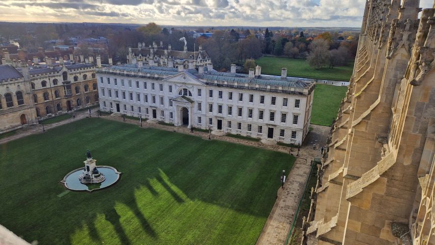 An aerial view of a large Georgian building with square lawn and a fountain in front of it.