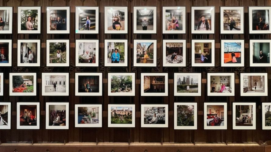 50 framed portrait photographs of women against a dark wood panelled background