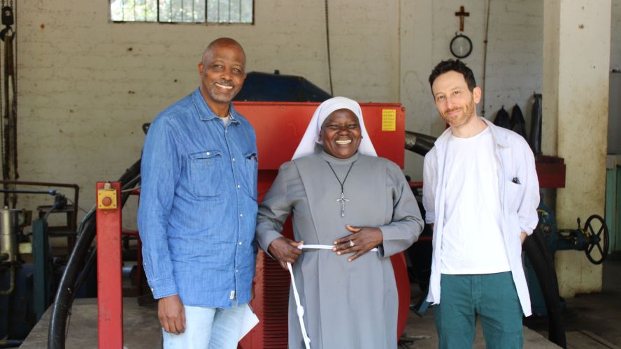 Two smiling men and a smiling woman in a nun's habit. 