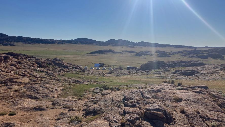 Sun rays across a rocky and grassy landscape in Mongolia