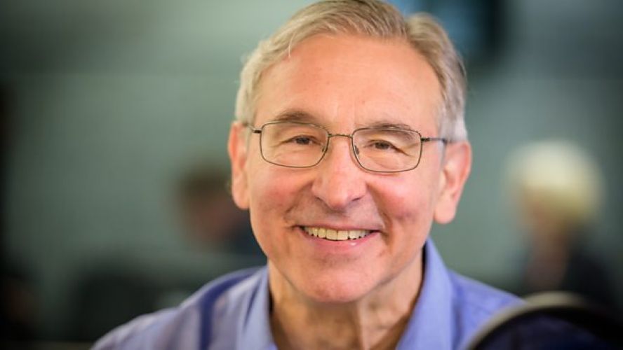 A white man with glasses and short grey hair wearing a light blue shirt