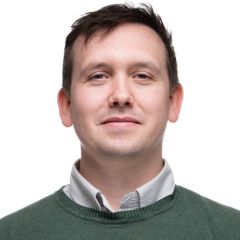 A man in a green jumper in front of a white background.