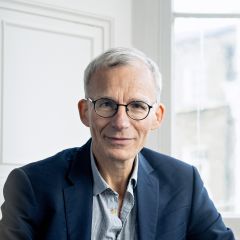 A white man with a dark jacket in front of a white background