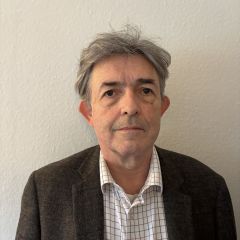 Hueston Finlay, a man with grey hair, wearing a light coloured shirt and a dark jacket