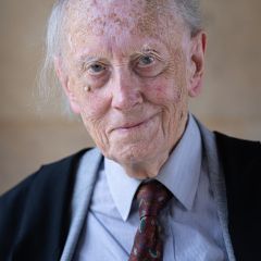 John Dunn, a smiling man with a black blazer and blue shirt