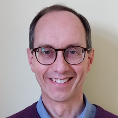 A smiling man wearing glasses