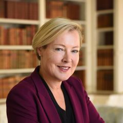 A white woman stands in front of bookcases