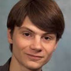 Ben Ravenhill, a smiling man with auburn hair against a grey background