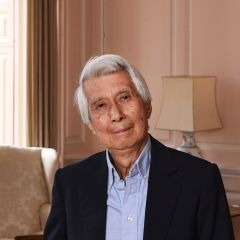 Charlie Loke, a smiling man with neat grey hair, a blue shirt and a black blazer in a pale pink room