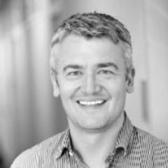 Cesare Hall, a black and white photo of a smiling man with short hair and a shirt