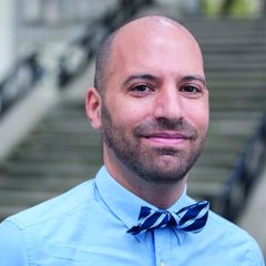 Dror Weil, a smiling bald man wearing a blue shirt and striped bow tie.