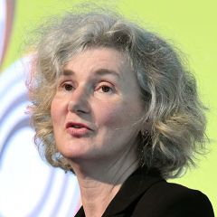 Fiona Godlee, a woman with short curly grey hair wearing a black blazer. She is giving a talk against a lime green background
