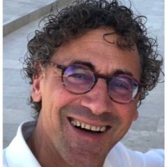 Francesco Colucci, a smiling man with curly dark hair, glasses and a white shirt