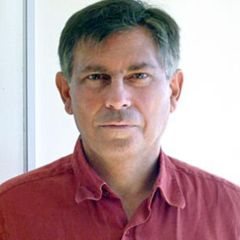George Efstathiou, a man with dark grey hair wearing a red shirt