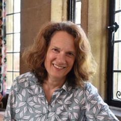 Godela Weiss-Sussex, a smiling woman with light brown shoulder-length hair sitting by a window