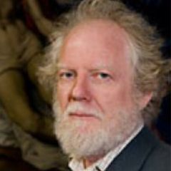 Jean Michel Massing, a man with mid length fair hair and a beard wearing a white shirt and a dark jacket. He is standing in front of a figurative painting