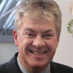 John Young, a smiling man with grey hair wearing a dark suit