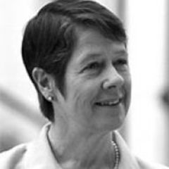 Judith Mayhew Jonas, a black and white image of a smiling woman with short dark hair wearing a white shirt and a pearl necklace