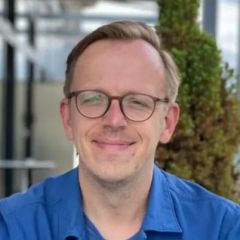 Marcus Boeick, a smiling man with short blonde hair, glasses and a blue shirt