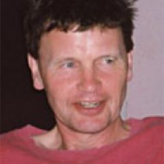 Michael Bate, a smiling man with short dark hair wearing a red t-shirt