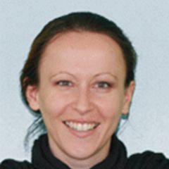 Mirjana Bozic, a smiling woman with dark tied back hair and a black polo neck jumper