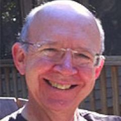 Peter Jones, a bald with glasses who is smiling broadly in the sun