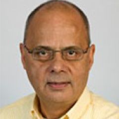 Richard Lambert, a man with very short dark hair and glasses wearing a yellow shirt