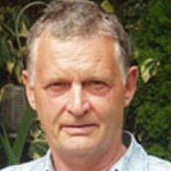 Robert Rowthorn, a man with short grey hair and a pale blue shirt. He is standing outdoors in front of some foliage