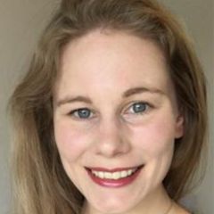 Tiffany Harte, a smiling woman with long blond hair and blue eyes against a grey background