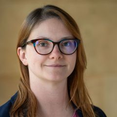 A white woman with brown hair and brown-framed glasses