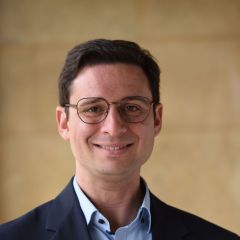 A man with brown hair and glasses