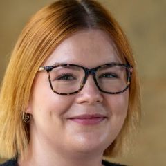 A woman with glasses and light red hair