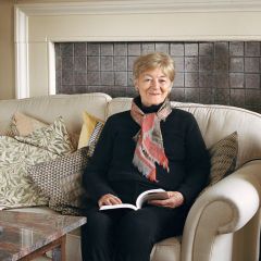 A woman sits on a sofa with a book open on her lap