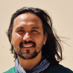 A man with dark shoulder length hair and a beard