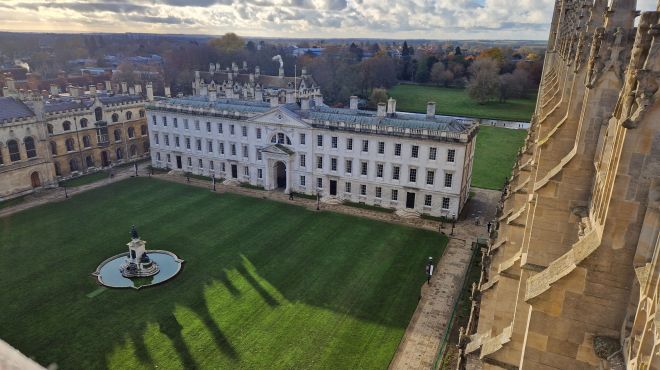 An aerial view of a large Georgian building with square lawn and a fountain in front of it.