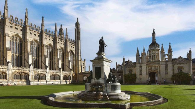 King's College first court. A central fountain stands on a large green lawn with the Chapel to the left and the gatehouse to the right.